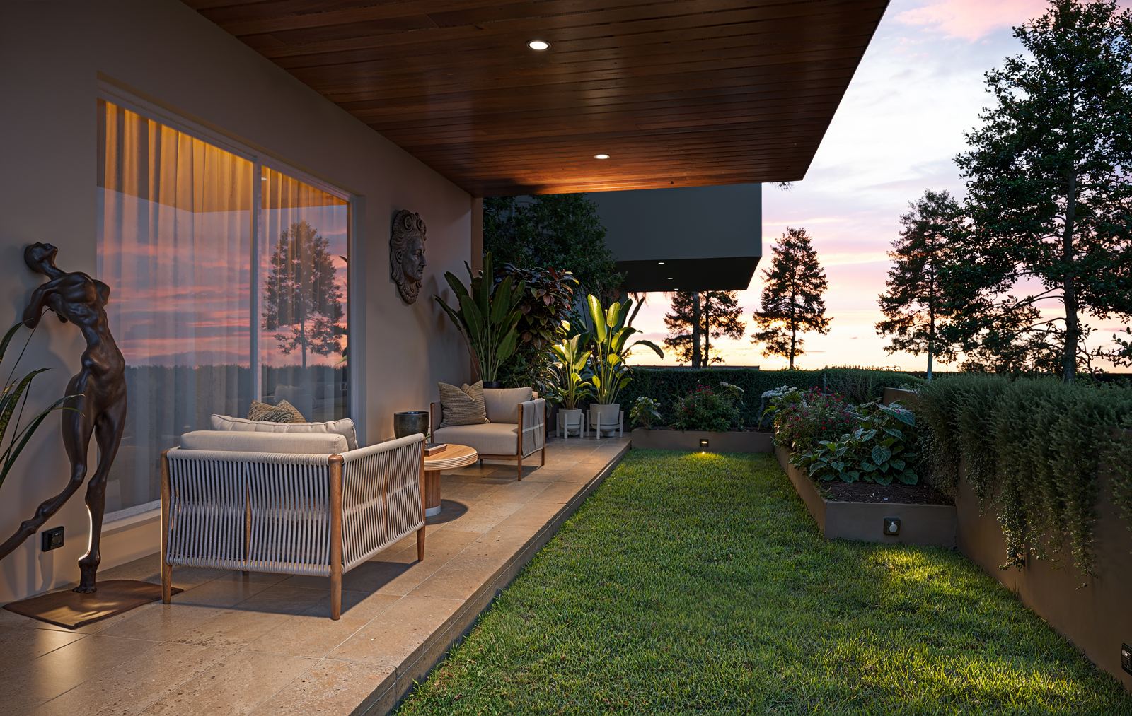 A landscaped garden deck with seating and flowering borders.