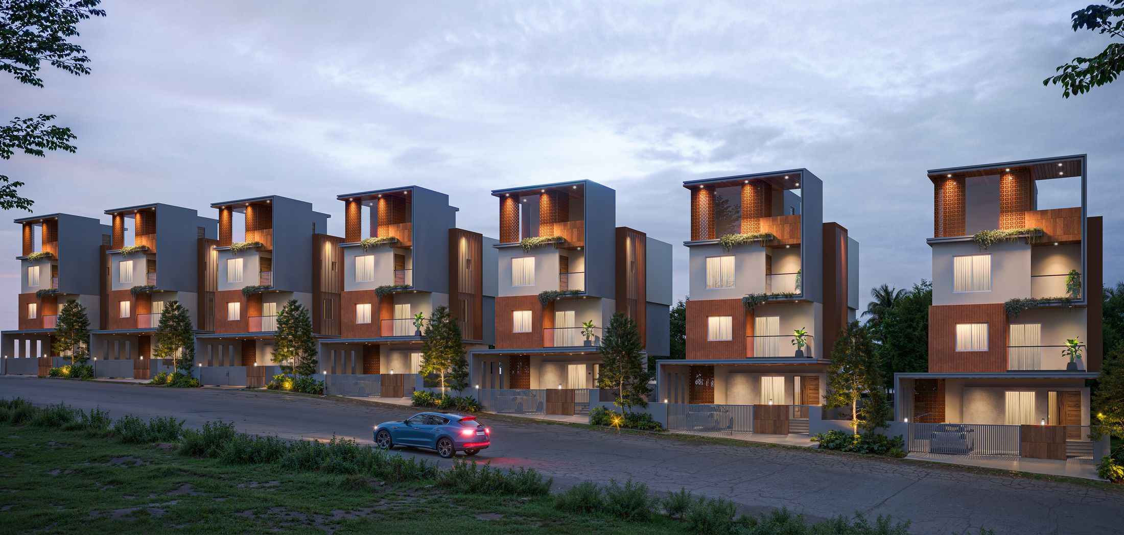 A row of four-storey villas at dusk, their terraces lit behind terracotta screens.